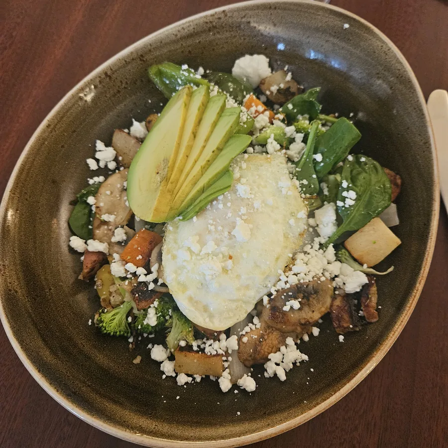 A garden veggie hash bowl — roasted vegetables, broccoli and spinach with feta, avocado and a farm egg.