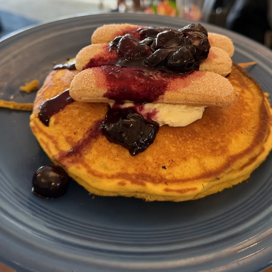 Weekend special — lemon-tiramisu pancakes topped with cherry compote and ladyfingers on a blue plate.